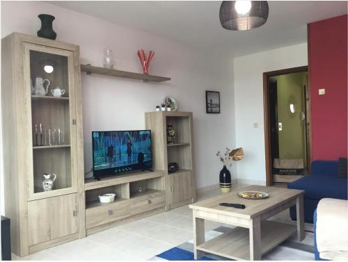 ein Wohnzimmer mit einem TV und einem Tisch in der Unterkunft Cómodo piso en Camino Inglés (a 10 min de Santiago) in Sigüeiro