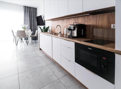 une cuisine avec des armoires blanches et un appareil noir dans l'établissement Aquarius Residence Apartament 104, à Boszkowo