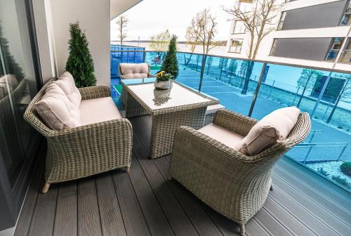 um pátio com cadeiras de vime e uma mesa na varanda em Aquarius Residence Apartament 104 em Boszkowo