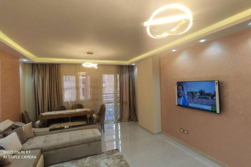 uma sala de estar com um sofá e uma televisão na parede em شقة للإيجار المفروش المدد القصير بكمبوند سما القاهرة. no Cairo