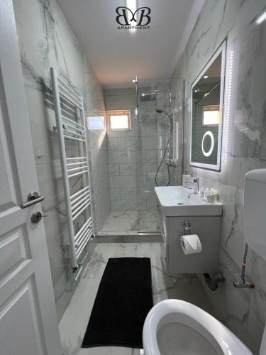 a white bathroom with a toilet and a sink at B&B Apartment in Oţelu Roşu