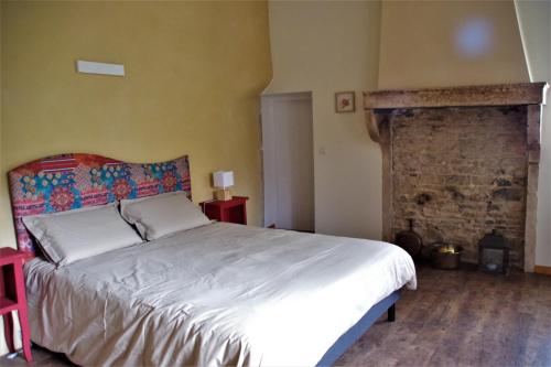 een slaapkamer met een groot bed en een bakstenen muur bij Le vieux pont in Saint-Julien