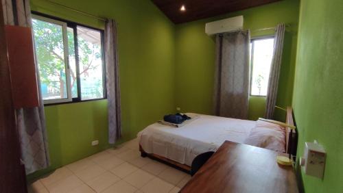 Casas Guanacaste Marbella في Marbella: غرفة نوم بجدران خضراء وسرير وطاولة