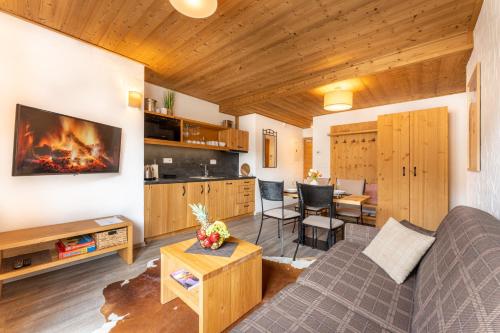 ein Wohnzimmer mit einem Sofa und einem Tisch sowie eine Küche in der Unterkunft Apartmán SAFFRON Chalet JASNÁ in Demänovská Dolina
