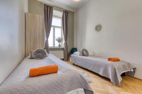 a bedroom with two beds with orange pillows on them at Historic Residence Apartments at Old Town in Tallinn
