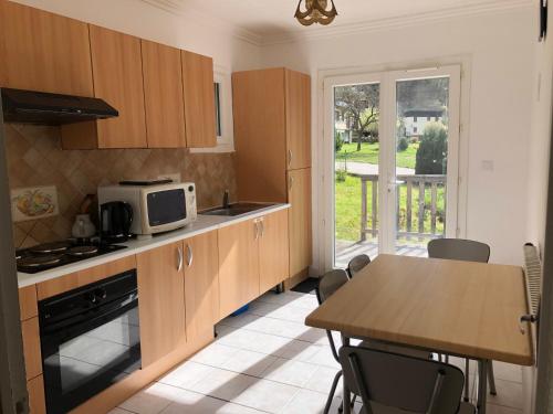 a kitchen with wooden cabinets and a table with a microwave at Au Cœur des montagnes in La Chalp