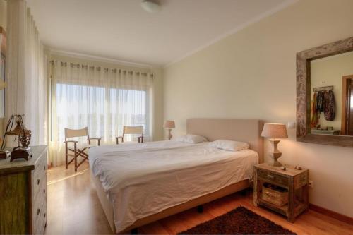 1 dormitorio con 1 cama grande y espejo en Vila Vida, en Ferragudo