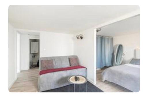 a bedroom with a bed and a couch and a table at Appartement 200 m plage avec terrasse et jardin in Royan