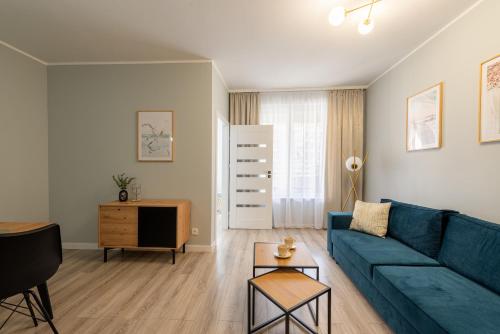 a living room with a blue couch and a table at Apartamenty Sunline Kołobrzeg in Kołobrzeg