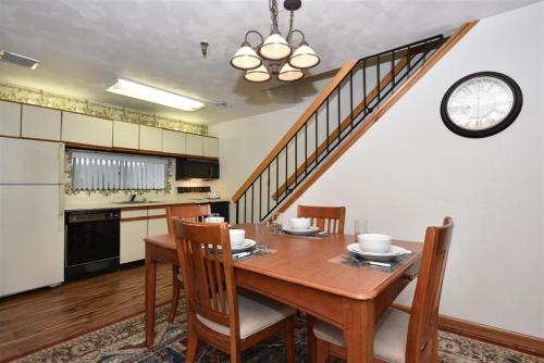 Seven Springs Stoneridge 3 Bedroom & Loft Standard Condo, walking distance to slopes! condo في Champion: طاولة طعام مع كراسي وساعة على الحائط