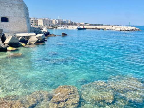 a body of water with rocks and a lighthouse at Dimora nel Palazzo Ducale in Giovinazzo