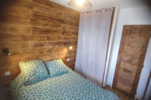 1 dormitorio con 1 cama con pared de madera en Appartement Valmeinier 6pers, en Valmeinier