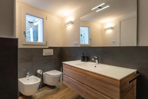 ein Badezimmer mit einem Waschbecken, einem WC und einem Spiegel in der Unterkunft A CASA DI LUPO in Cison di Valmarino