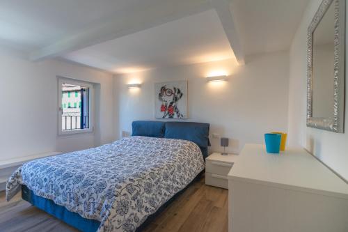 a white bedroom with a blue bed and a window at A CASA DI LUPO in Cison di Valmarino