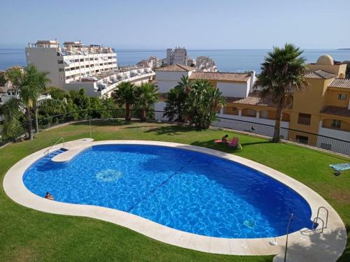 una gran piscina en medio de un césped con edificios en Estudio en Nueva Torrequebrada, en Benalmádena