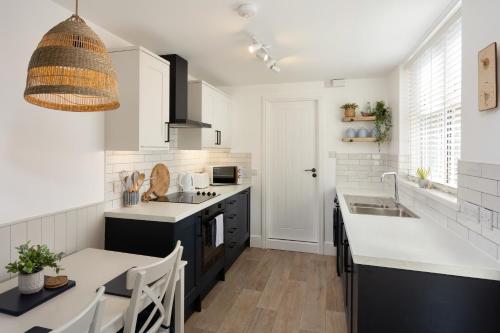 a kitchen with white cabinets and a sink and a table at Low Tide @ Filey. Close to Beach. Dog Friendly. in Filey