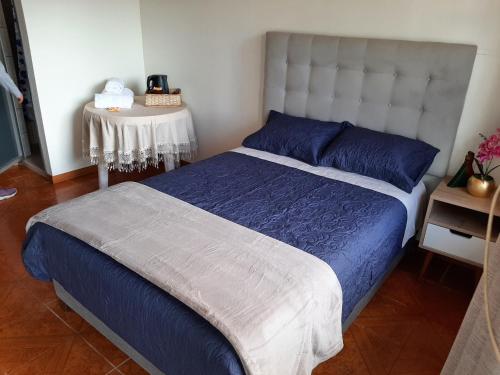 a bedroom with a bed with blue sheets and a table at Casa Familia Rubio in Oxapampa