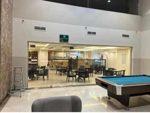 a pool table in a room with tables and chairs at Altelal Tower Apartment in Makkah