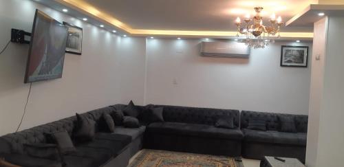 a living room with a black couch and a chandelier at Aswan Nile view palace in Naj‘ al ‘Amrāb