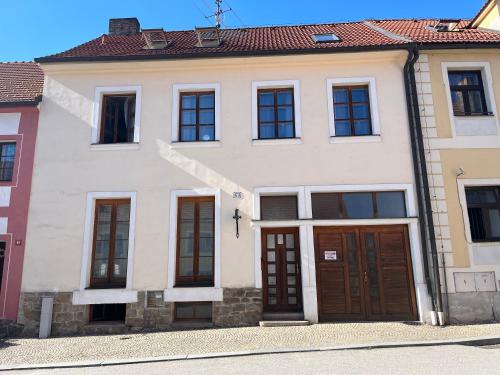 a white house with brown doors and windows at Ubytování U Hradu in Nové Hrady