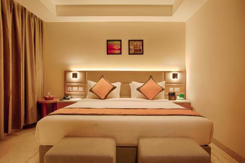 a bedroom with a large bed with two chairs at Sunhill Portico in Siliguri