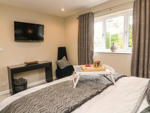 a bedroom with a bed and a tv on the wall at Kilmory Lodge in Poulton le Fylde