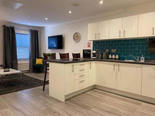 a kitchen with white cabinets and a green tile wall at Modern 3 bedroom apartment close to the city centre in Liverpool