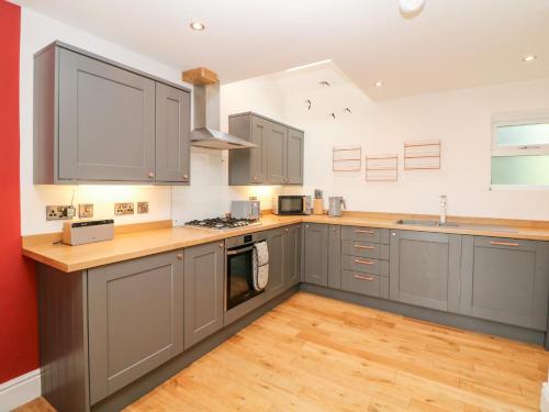 a kitchen with gray cabinets and wooden floors at The Old Stables in Matlock