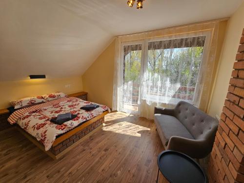 a bedroom with a bed and a chair and a window at Szilvás 10 in Szigliget