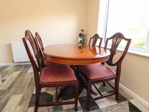a wooden table with four chairs and a window at Bungalow by the Sea in Cleveleys