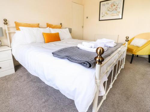 a bedroom with a large bed with white sheets and orange pillows at Bungalow by the Sea in Cleveleys