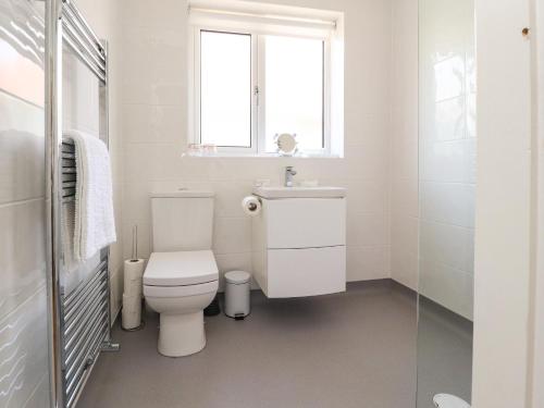 a white bathroom with a toilet and a sink at Bungalow by the Sea in Cleveleys