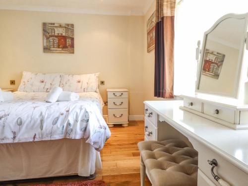 een slaapkamer met een bed, een dressoir en een spiegel bij 1 The Beeches in Llangollen