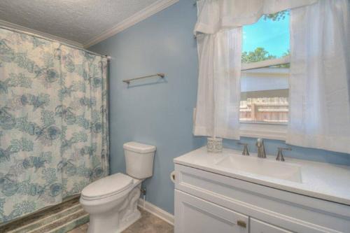 a bathroom with a toilet and a sink and a window at Beach Lovin/sleeps 10/2 blocks to beach/pets ok in Myrtle Beach