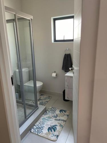 a bathroom with a glass shower and a toilet at Lovely Cozy Apartment in Midrand