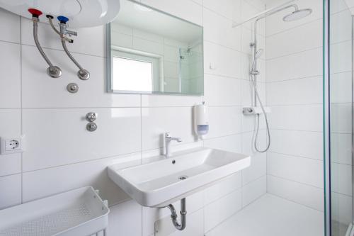 a white bathroom with a sink and a shower at Holiday house in Terme Čatež in Brežice