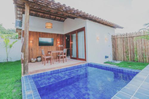een villa met een zwembad, een tafel en een tv bij Pousada Vilagoa in Coqueiro Sêco