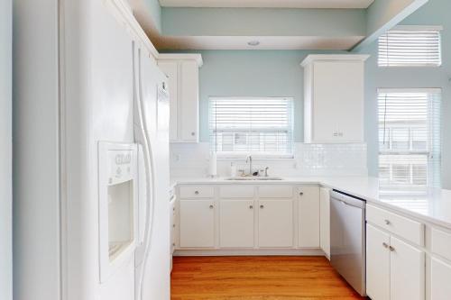 a kitchen with white cabinets and a white refrigerator at Serenity On The Bay in Fairhope
