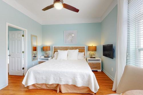 a bedroom with a white bed with a ceiling fan at Serenity On The Bay in Fairhope
