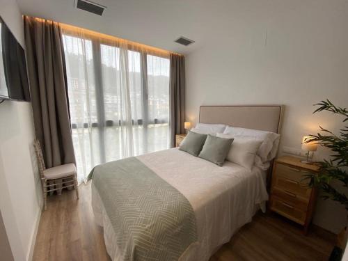 sypialnia z dużym łóżkiem i dużym oknem w obiekcie A PONTEVELLA Alojamiento Boutique, Sobradelo w mieście Sobradelo