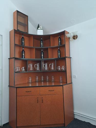 a wine rack with bottles and glasses on it at Cabane Areama Neagra in Izvoru Mureşului