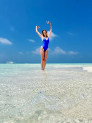 a woman in a blue bathing suit standing on a beach at Konut by Thakuru in Guraidhoo