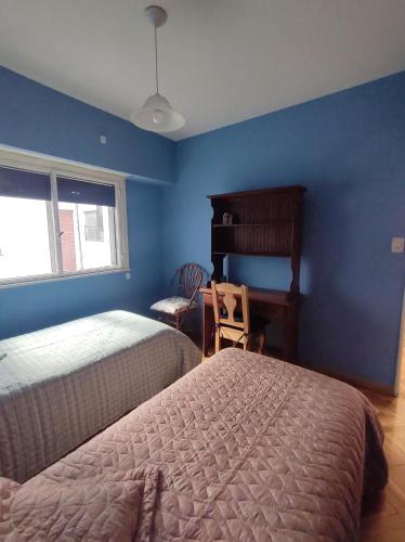 1 dormitorio con paredes azules, 2 camas y silla en Excelente depto 3 ambientes en Buenos Aires