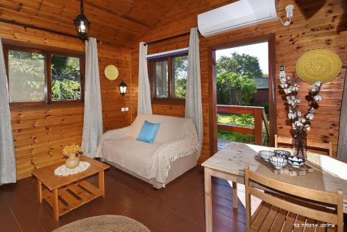 Dormitorio de una cabaña de madera con cama y mesa en בקתה בתמרים en Moshav Ramot