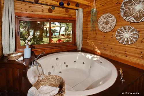 a bath tub in a wooden cabin with a window at בקתה בתמרים in Moshav Ramot