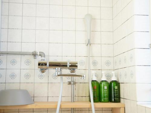 Baño de azulejos blancos con botellas verdes en un estante en HataraColiving - Vacation STAY 22651v, en Chichibu