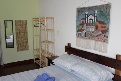 a bedroom with a bed and a painting on the wall at Pousada Chateau Sophie in Itanhaém