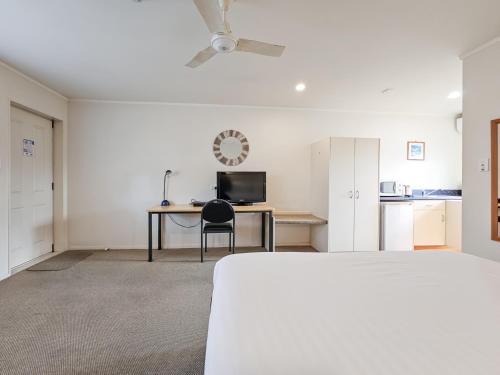 a bedroom with a bed and a desk with a computer at Captain Cook Motor Lodge in Gisborne