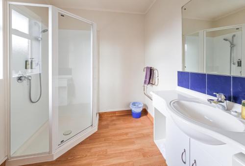 a bathroom with a white sink and a shower at Captain Cook Motor Lodge in Gisborne