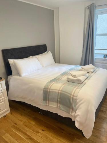 um quarto com uma cama com lençóis brancos e uma janela em Inverness Highland Apartment em Inverness